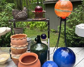 Assorted Garden Decor: Cast Iron Rooster, Glass Gazing Balls, Terracotta Pots, and Large Green Bottle