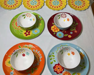 Lot 16: Laurie Gates floral ceramic dinnerware set with bowls, colorful plates, yellow scalloped plates, and red pedestal cups