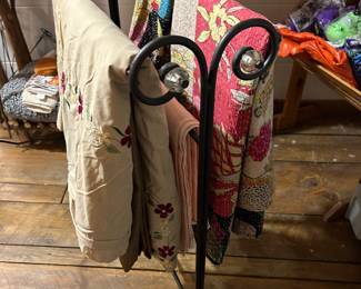 Decorative wrought iron quilt and blanket rack with scrollwork design and glass finial accents