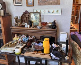 Framed art, clocks, brass candlesticks, ceramics, dolls, glass dishes, trays, yellow pitcher, boxes, and mixed tabletop finds.