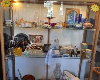 Colorful glass, apothecary bottles, tins, metalware, framed pieces, horse figures, natural decor, and cabinet curiosities.