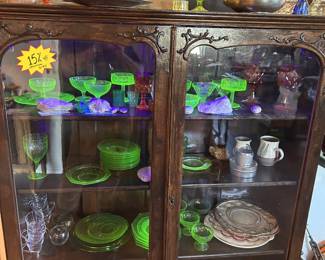 Glowing uranium/vaseline glass, colored glass, red glass stems, clear glassware, plates, natural accents, and decorative objects.