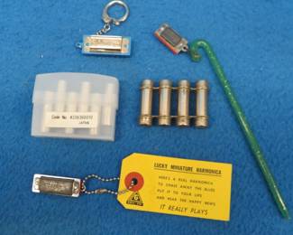 Lot 86. Five harmonica smalls: Lucky miniature harmonica made in Japan. Guitar pitch pipe. Violin pitch pipe. C.A. Seydel Sohne 4-hole blow only harmonica on a key ring. Illegible two-hole blow only 1" harmonica on a plastic candy cane.