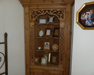 Rustic pine corner curio cabinet with ornate fretwork, picture frames