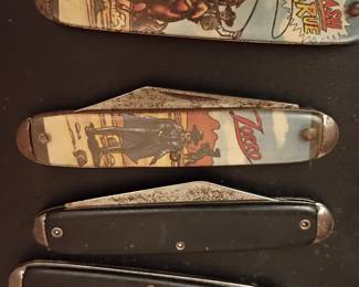 vintage folding pocket knives, and the top two collectible because of the graphic comic/western handles