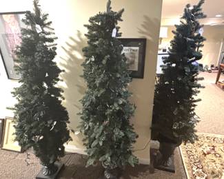 Three pre lit Christmas trees in planters.