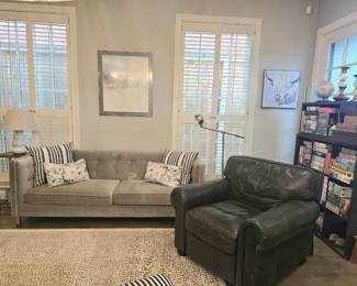 couch, brown leather chair, rug, throw pillows and lots of wall art