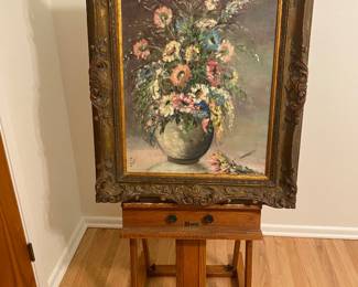 Large floral oil painting with intricate frame and vintage wooden easel. 