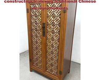 Lot 982 Tall, twodoor armoire of hardwood construction featuring traditional Chinese design elements