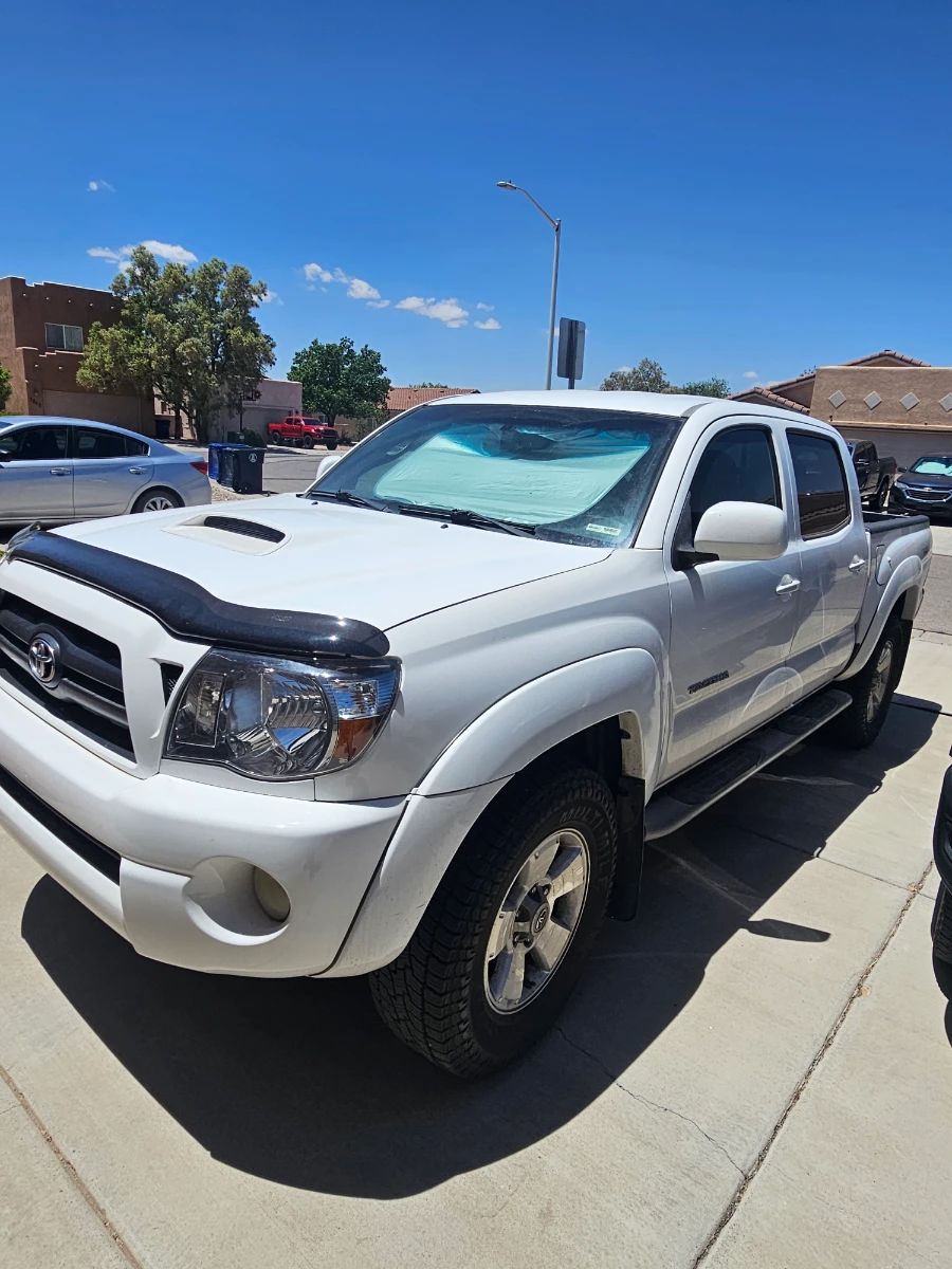 B‑I‑G Loaded • Variety*Toyota Tacoma (Double Cab)**  - Make: Toyota - Model: Tacoma - Trim: TRD (TRD badge visible on side) - Color: Super White - Cab: Double Cab - Hood: Scoop with bug deflector/hood guard - Wheels: TRD alloy wheels - Tires: All-terrain - Running Boards: Side steps - Tinted Windows: Yes - Sunshade: Windshield sunshade present - Paint Condition: Good - Registration: New Mexico - Year: TBD - VIN: TBD - Miles: TBD - Engine: TBD - Transmission: TBD - 2WD/4WD: TBD 