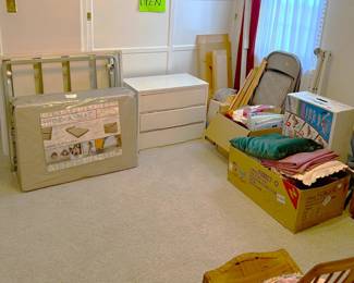 This is another view of the bedroom, with a three-drawer dresser, a few folding chairs, a folding bed (trundle?) with a Hide-A-Mat mattress.