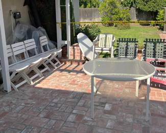 Outside there is a small collection of patio furniture, including the glass-top table, at at least three different types of chairs.