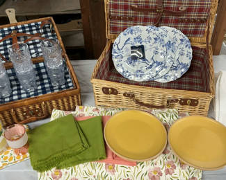 Lot 144: Wicker picnic baskets with blue floral and yellow dinnerware, glassware, and linens