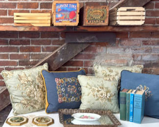 Lot 299: Vintage home décor collection: pillows, picture frames, crates, plate, mirror, and books