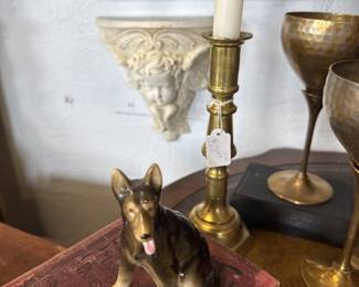 ceramic dog figurine, vintage books, brass candlestick, brass goblets, shelf