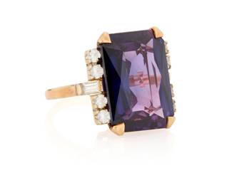 1134 A 10K Gold and Synthetic Doublet Sapphire Ring Centering a mixed-cut synthetic purple doublet sapphire measuring approximately 17.80 x 13.00 x 6.90mm, accented by baguette and round near colorless stones Size: 6.5 9.33 grams gross This lot is being offered with no reserve Estimate: $300 - $500