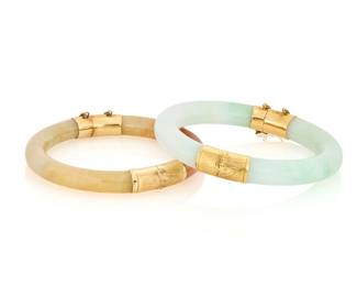 1064 Two 14K Gold and Jade Bangles Both of a hinged design featuring green jade and yellowish orange jade 2 pieces Inner circumference: 7 in. and 7 1/4 in. 101.7 grams gross This lot is being offered with no reserve Estimate: $600 - $800