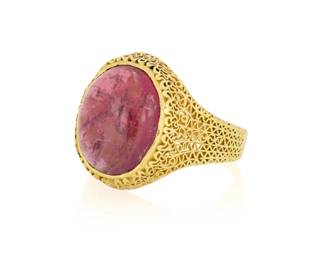 1061 An 18K Gold and Rubellite Tourmaline Ring Featuring an oval rubellite double cabochon weighing approximately 8.50 carats, set in an intricate open work design Size: 8 1/4 7.2 grams gross This lot is being offered with no reserve Estimate: $1,000 - $2,000