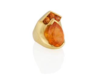 1149 An 18K Gold and Mandarin Garnet Ring Centering a pear-shaped mandarin garnet weighing approximately 17.60 carats, accented by three round mandarin garnets Size: 7 3/4 21.3 grams gross Estimate: $2,500 - $3,500