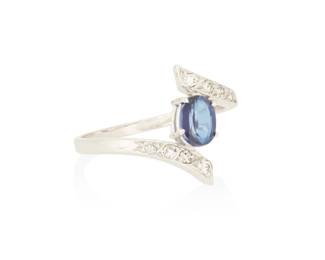 1048 An 18K White Gold, Sapphire and Diamond Ring Centering an oval sapphire weighing approximately 0.90 carat accented by round and single-cut diamonds set in a bypass design Size: 8 3/4 3.56 grams gross Estimate: $1,000 - $2,000