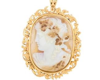 1021 An 18K Gold and Double-Sided Agate Cameo Pendant Centering an oval carved agate double cameo featuring a Bacchus motif and female profile set in an ornate floral frame Measures: 2 1/2 x 1 1/2 in. 22.1 grams gross Estimate: $800 - $1,200