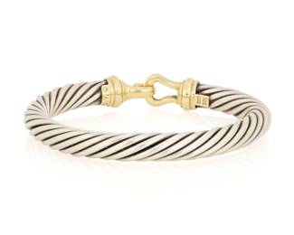 1178 David Yurman: A 14K Gold and Silver Cable Cuff Featuring a sterling cable design finished with a 14k gold hook clasp, signed D.Y. Inner circumference: 6 1/4 in. 43.7 grams gross This lot is being offered with no reserve Estimate: $400 - $600