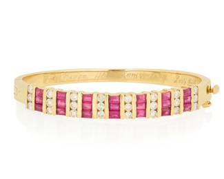 1004 A 14K Gold, Ruby and Diamond Bangle Of a hinged design featuring alternating rectangular step-cut rubies and round diamonds, estimated total diamond weight 1.68 carats Inner circumference: 7 in. 29.0 grams gross Estimate: $2,000 - $3,000