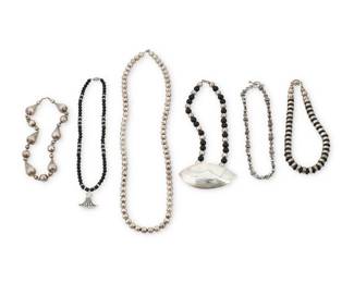 1194 A Group of Silver and Hardstone Necklaces Mid/late 20th century Five variously marked for maker and/or for sterling: MFA / ND STG 14K Comprising six single strands, three with hardstone or glass beads, one with an Egyptian style pendant, one with a large modernist oval plaque, and one with chunky sterling silver teardrop beads alternating with small 14K gold beads 6 pieces 30 1/2 in. L to 15 1/2 in. L 339.5 grams gross This lot is being offered with no reserve Estimate: $200 - $400