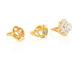 1108 A Group of Three 18K Gold Rings Of swirling designs accented by round diamonds, an oval blue diamond and a round orange diamond 3 pieces Sizes: 6 1/2 27.3 grams gross Estimate: $2,200 - $2,800
