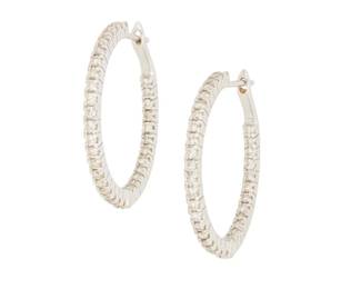 1052 A Pair of 18K Gold and Diamond Hoops Featuring round diamonds set half inside and half outside of the hoop weighing approximately 1.12 carats total 2 pieces Measures: 1 1/8 in. 6.7 grams gross Estimate: $1,000 - $2,000