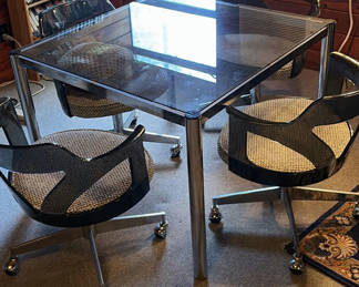 Lot 23: Glass-top dining table with four chrome-and-black swivel chairs