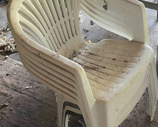 Lot 77: Stacked white plastic patio chairs and a black metal pit