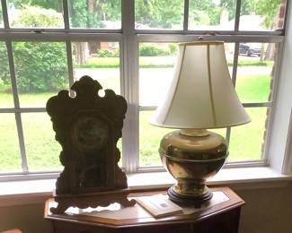 Clock with brass lamp sitting on cabinet with marble like top. Cabinet: Price: $90.00
