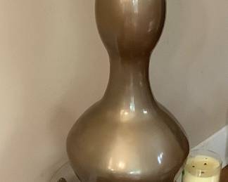 Tall glass bottle on round stand with glass.