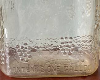 M19 - $20. Garrett's 1 Gallon American Wine. The glass is a faint peach color. Measures 6.75" wide x 5.25" x 11.5" tall.