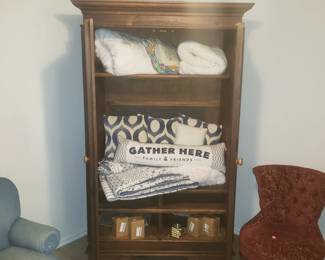 Antique armoire with king size linens and a petite slipper chair