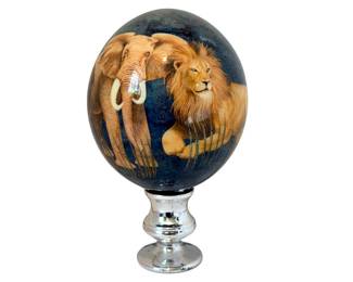  Hand-blown Ostrich Eggshell Art Piece.  This hand-blown ostrich eggshell art piece features the African "Big Five" wildlife—lion, elephant, leopard, rhinoceros, and buffalo—set against a deep teal-mottled background. The Big Five safari animals represent the most iconic and popular wildlife to view in the African wilderness. Plated silver stand. 7" tall