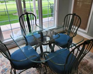 Glass top table with 4 Wright iron blue cushioned chairs
