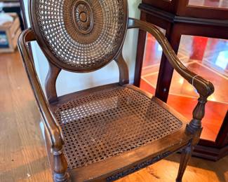Caned balloon-back armchair with carved wood frame