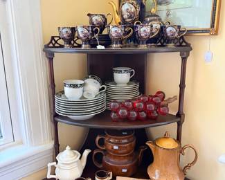 Demilune display table with porcelain tea sets and teapots