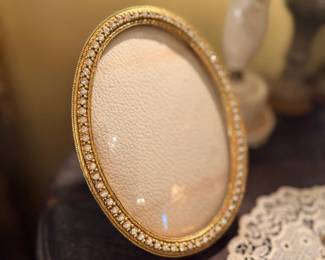 Oval gold-framed vanity mirror with beaded edge