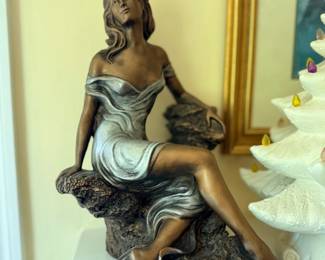 Bronze-finish sculpture of seated woman in flowing gown