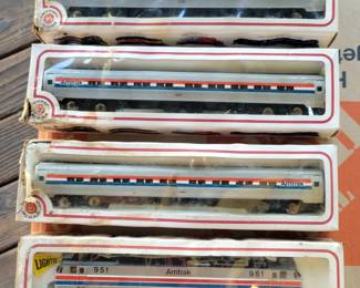 Four HO-scale model train cars are shown here.  All of them are Amtrak train cars.
