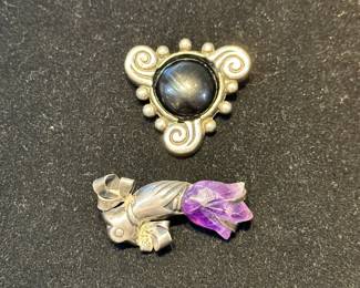 Signed William Spratling silver and onyx brooch, and an unsigned Spratling silver hand holding carved amethyst flower brooch