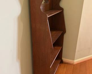 Antique bookshelf with carved details and small mirror.