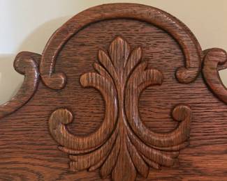 Antique bookshelf with carved details and small mirror.