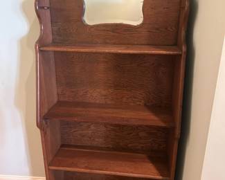 Antique bookshelf with carved details and small mirror.