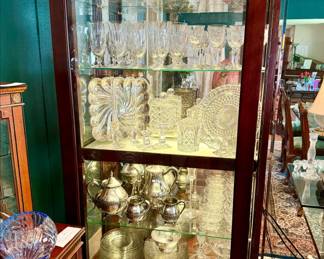 Sliding glass curio full of glassware, crystal, and silver.