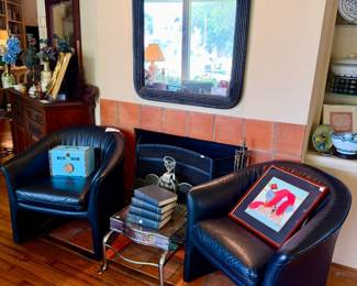 Pair of black leather barrel chairs.