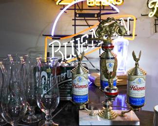 Vintage Hamm's Beer Trophy & Breweriana Display A true conversation piece for the collector, bar enthusiast, or man cave owner! This unique vintage display features a custom trophy constructed from Hamm's Beer cans, mounted on a marble base and topped with a detailed motorcycle rider figure. Highlights include: Vintage Hamm's Beer can trophy with patriotic red, white, and blue accents Detailed motorcycle rider topper Marble base with brass-tone eagle finials Vintage Hamm's and Pilsner beer glassware Classic breweriana collectibles and bar memorabilia Displayed alongside vintage neon beer signs and home bar décor Whether you're a breweriana collector, motorcycle enthusiast, or simply appreciate unusual vintage advertising pieces, this one-of-a-kind trophy is sure to attract attention.